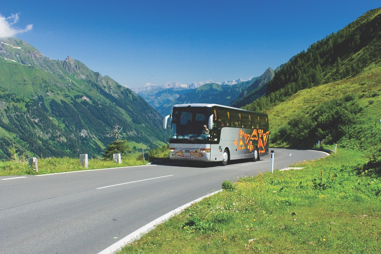 Bus with tourists driving uphill in Alps
