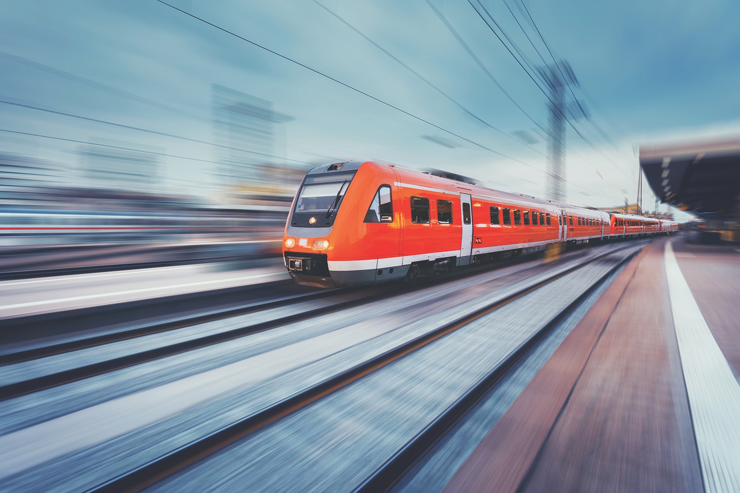 Modern high speed red passenger commuter train in motion at the railway platform. Railway station. Railroad with motion blur effect. Industrial concept landscape with instagram toning. Transportation